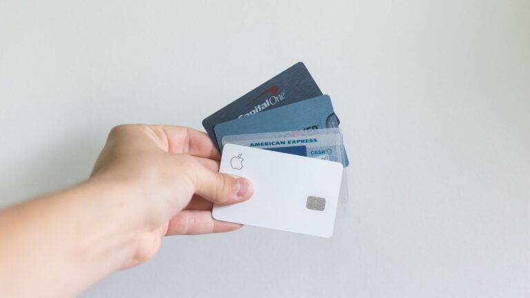 hand holding four white and blue credit cards